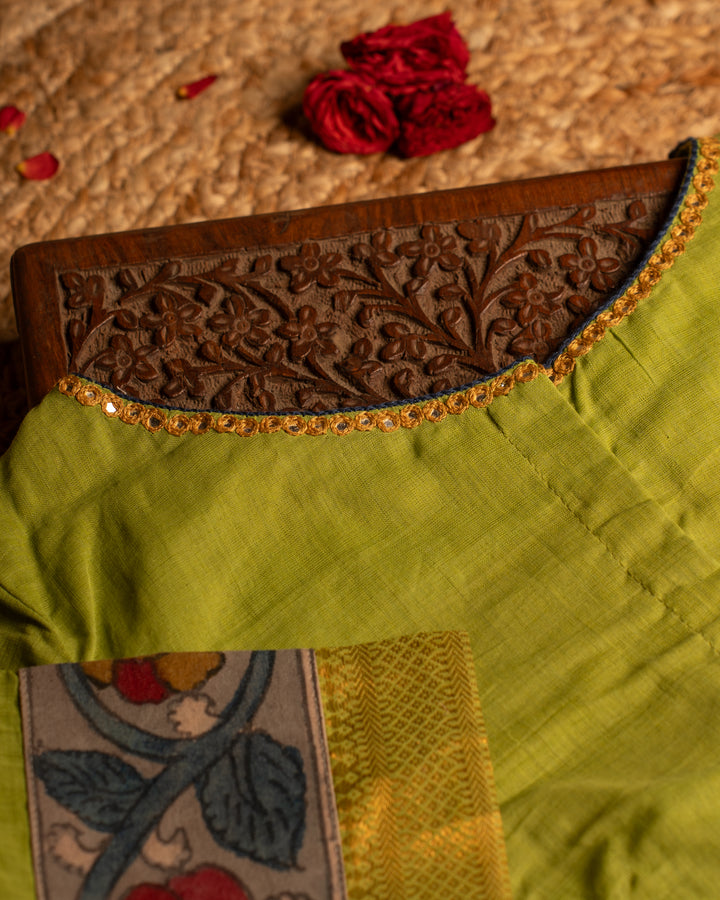 Back side green blouse best suitable for silk saree kept on the jute round mat.