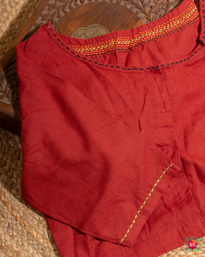 Beautiful red embroidery blouse which would suit any silk saree is kept upon a mat and a wooden designer box.