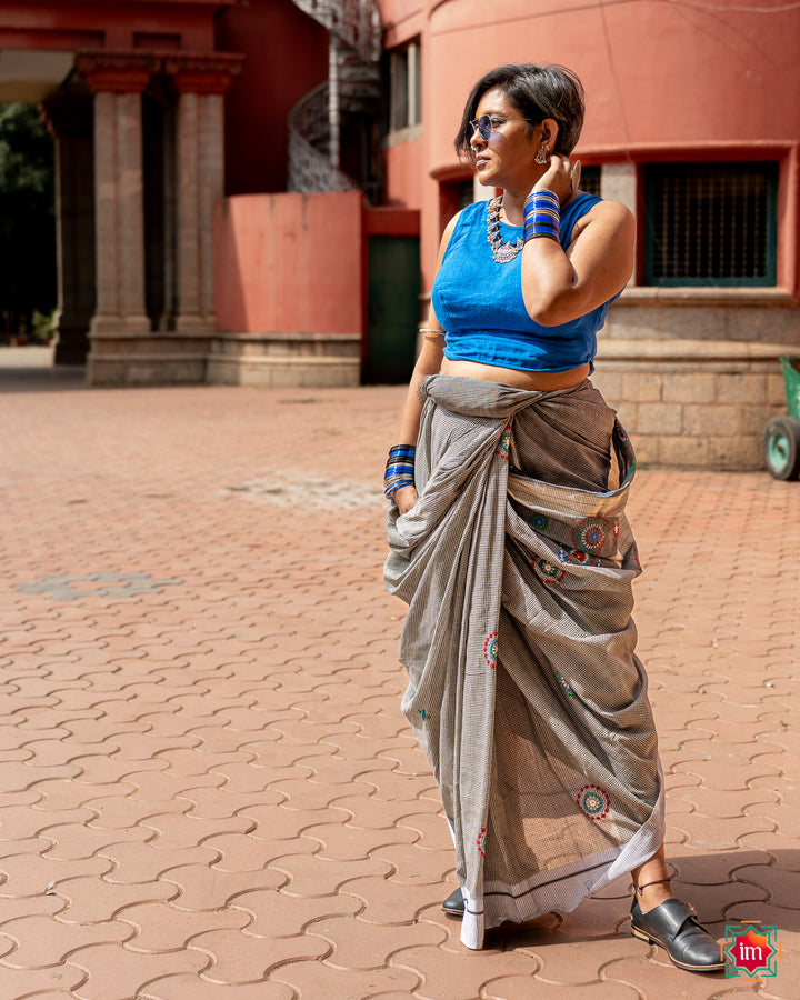 A women posing beautifully by wearing a beautiful grey handloom cotton saree on a old street.