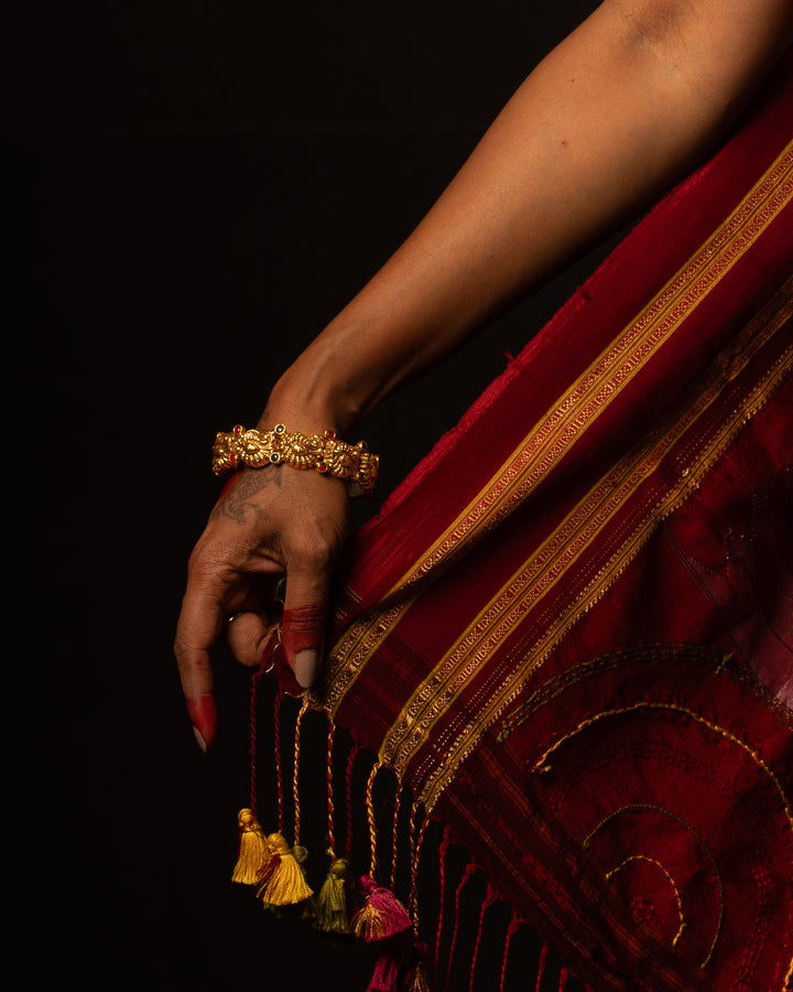 A women is dressed up and is posing by wearing beautiful purple saree with matching jewelry.