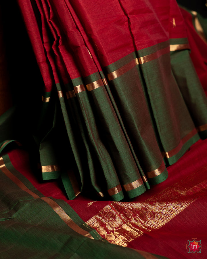 Beautiful red handloom saree is pleated and displayed on the floor.