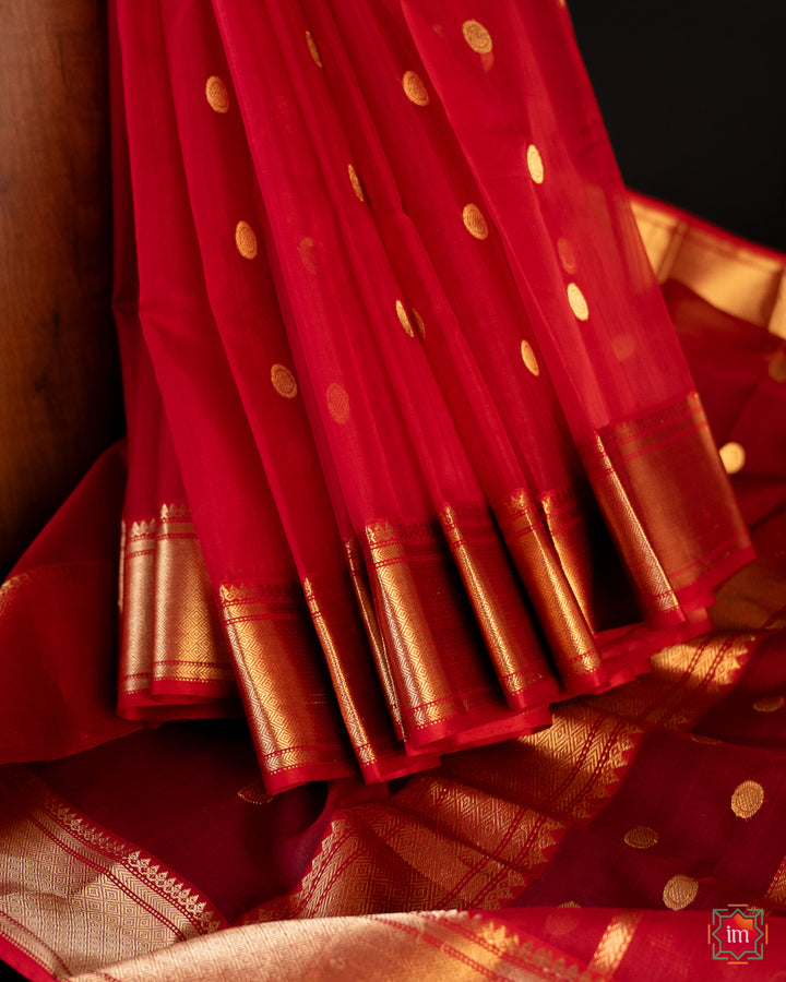 Beautiful red silk saree is pleated and displayed on the floor.