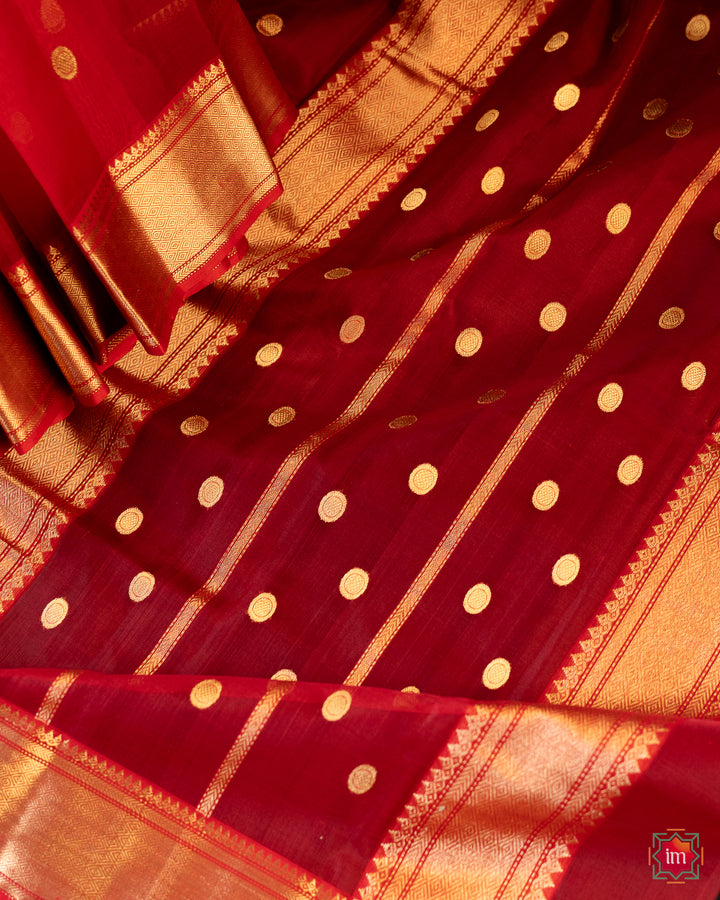 Beautiful red silk saree is pleated and displayed on the floor.