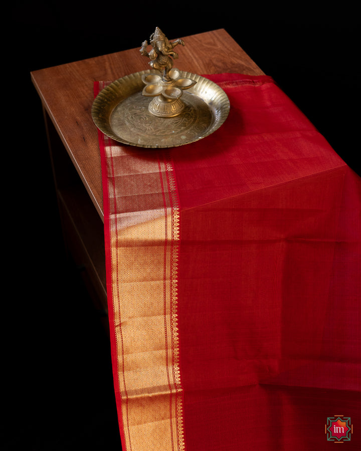 A part of the red silk saree is kept on a bench with ganapati statue upon it.