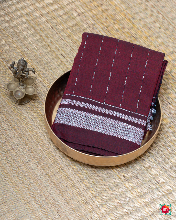 Elegant honey red handloom cotton saree kept on a plate with ganapati statue beside which are kept upon the mat.