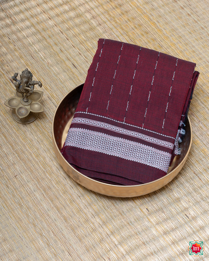 Elegant honey red handloom cotton saree kept on a plate with ganapati statue beside which are kept upon the mat.