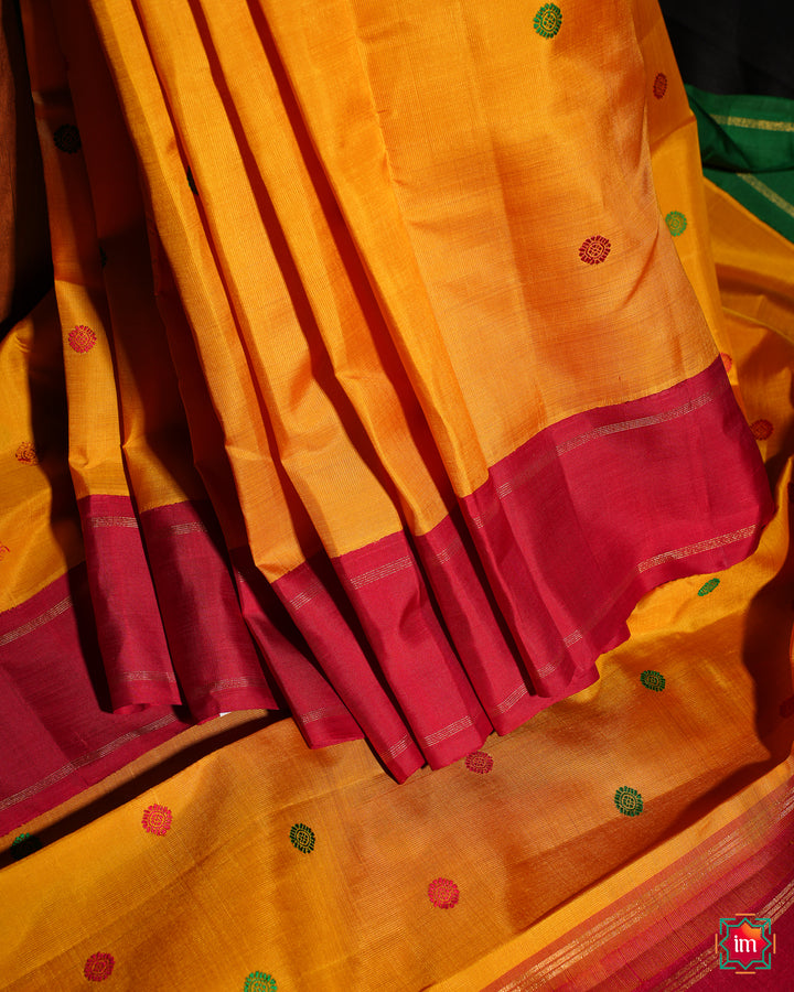 Yellow Red Ganga Jamuna Kanjivaram silk saree is pleated and displayed on the floor.