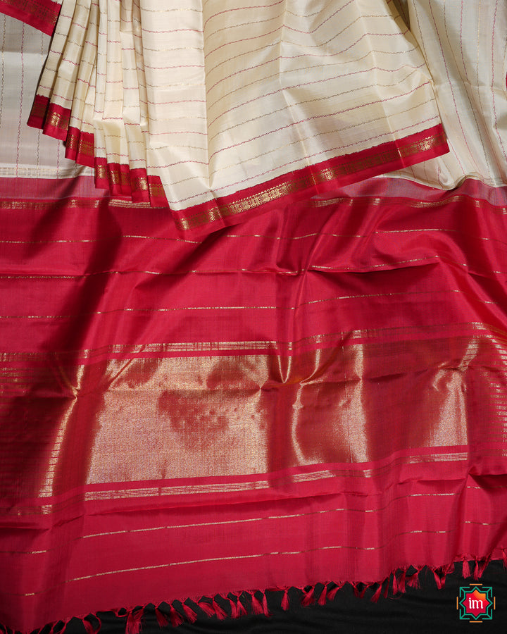 White Red Kanjivaram  Silk Saree is pleated and displayed on the floor.