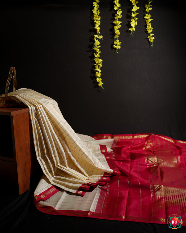 White Red Kanjivaram  Silk Saree  is displayed on the floor with black background and yellow flowers hanging above.