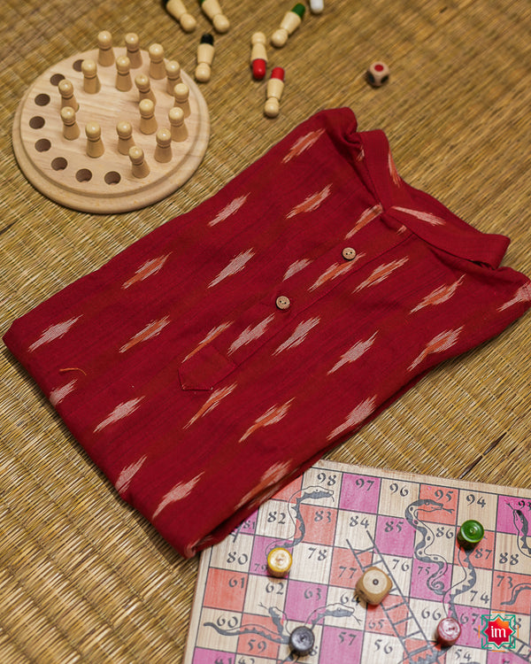 Beautiful red girl kurta which is kept on a mat background with some children indoor games which are kept beside.