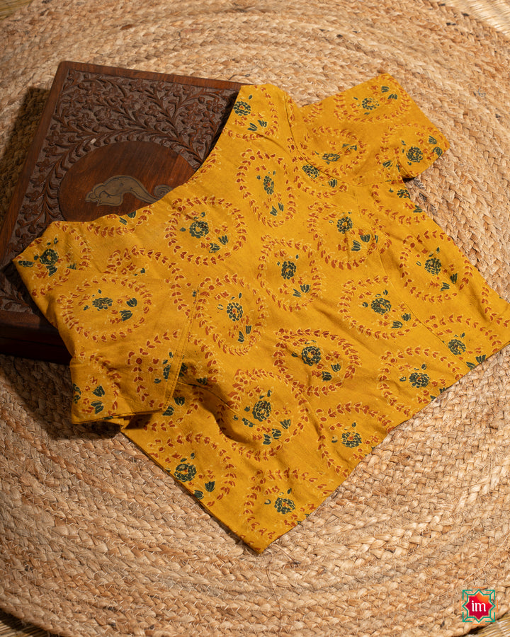 Elegant blouse which would suit any silk saree is kept upon a mat and a wooden designer box.
