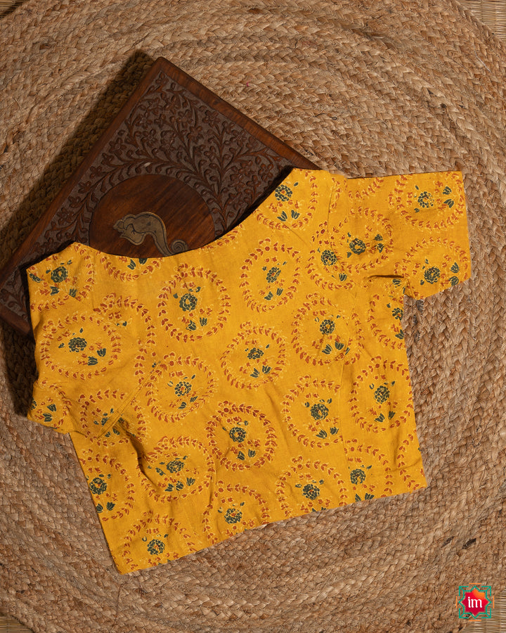 Elegant blouse which would suit any silk saree is kept upon a mat and a wooden designer box.