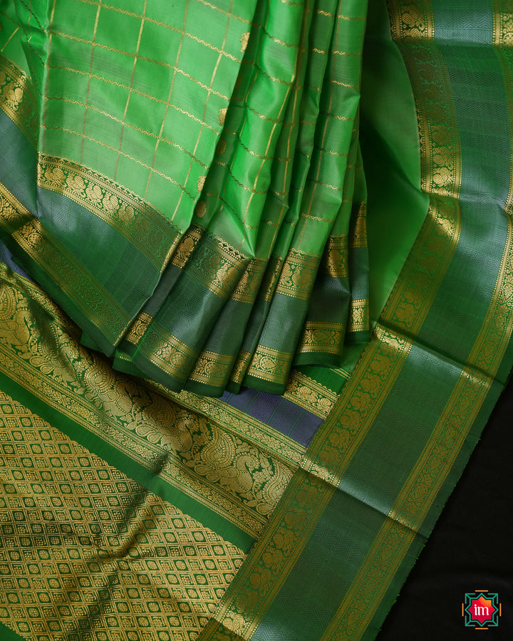Beautiful Rexona Green Kanjivaram Saree is displayed on the floor with black background.