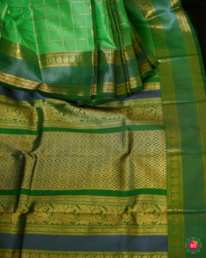 Beautiful Rexona Green Kanjivaram Saree is displayed on the floor with black background.