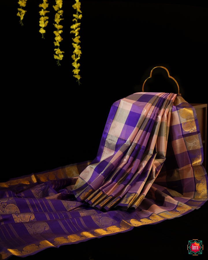 Beautiful Multicolour Kanchi Silk Saree is displayed on the floor with black background and yellow flowers hanging above.