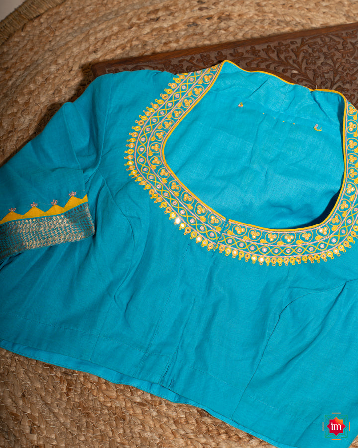Elegant blue embroidery blouse which would suit any silk saree is kept upon a mat and a wooden designer box.