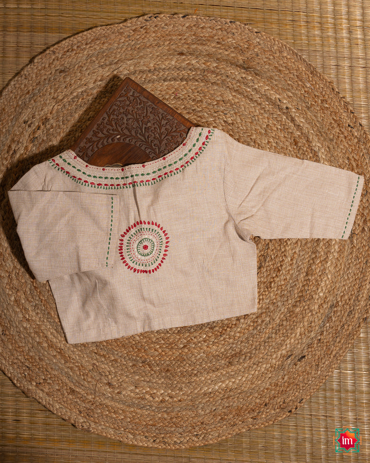 Elegant off-white embroidery blouse which would suit any silk saree is kept upon a mat and a wooden designer box.