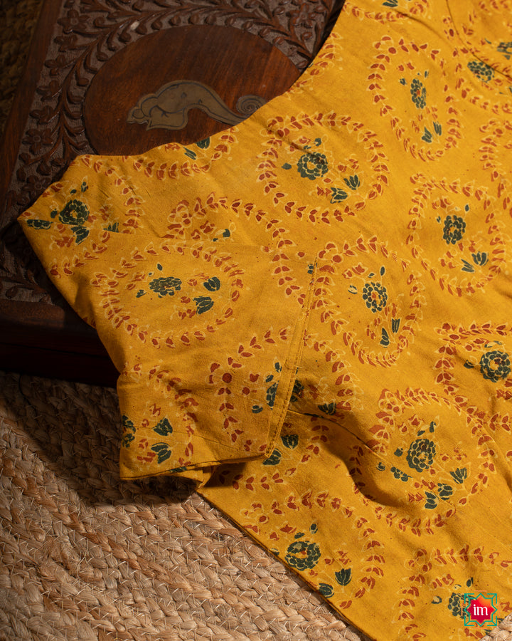 Elegant blouse which would suit any silk saree is kept upon a mat and a wooden designer box.