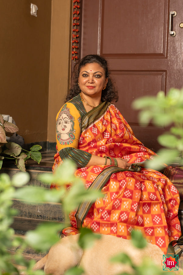 A women is dressed up and is posing outdoor by wearing beautiful red yellow silk saree with matching jewelry.