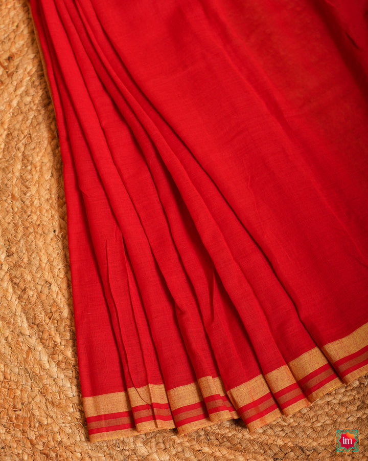 Beautiful cherry red handloom saree is pleated and displayed on the floor.