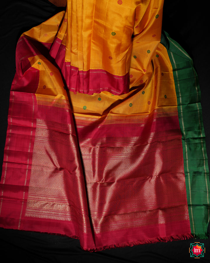 Yellow Red Ganga Jamuna Kanjivaram silk saree is pleated and displayed on the floor.